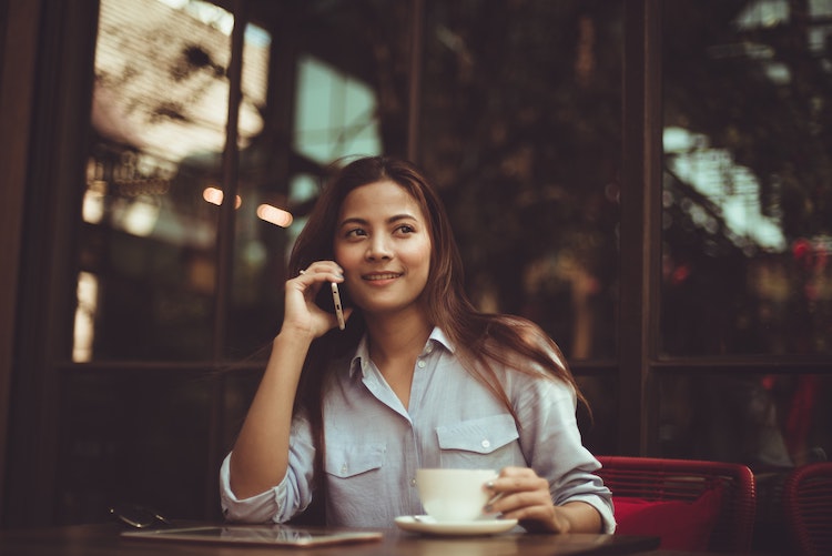 woman smiling and talking on her phone in a coffee shop