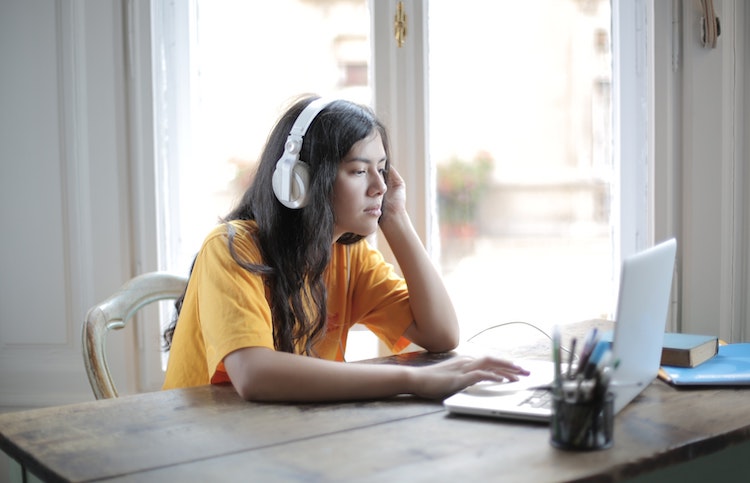 woman wearing a headset and listening to music on her laptop