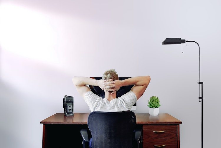man taking a rest with his hands on his head in front of the computer