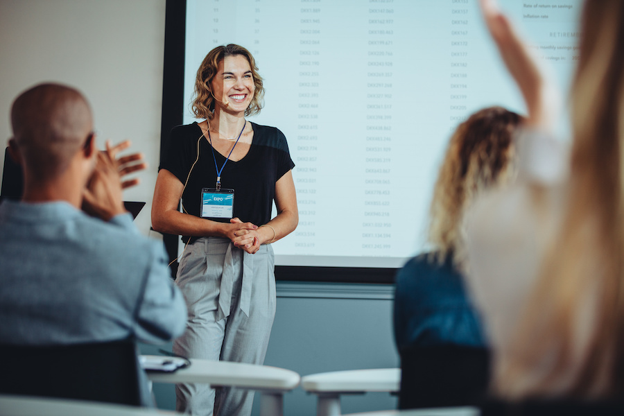woman smiling receives applause at a public speaking event