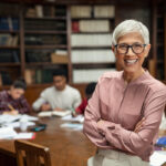 older college professor with eyeglasses smiling towards the camera