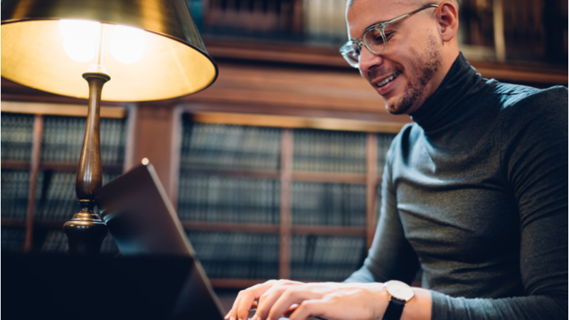 Man happily writing his dissertation abstract in a library