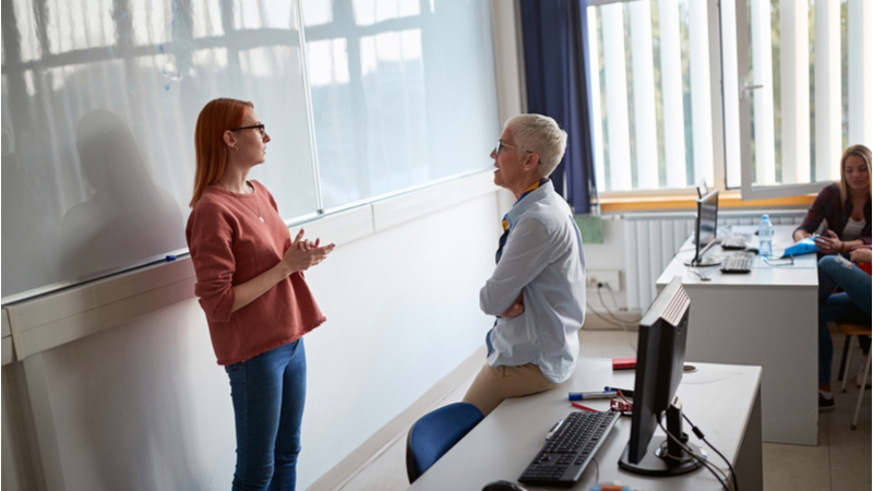 red haired student explaining stuff in a classroom with her professor looking at her