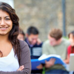 Woman smiling at the camera with her college friends behind her