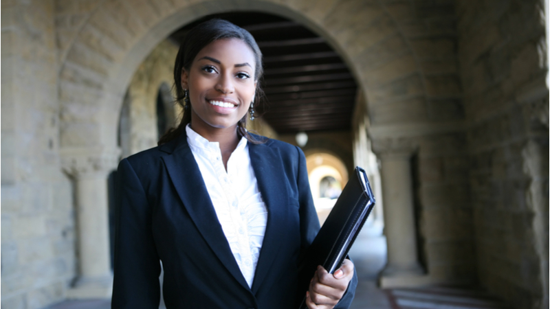 black woman in a suit holding a notebook on university campus
