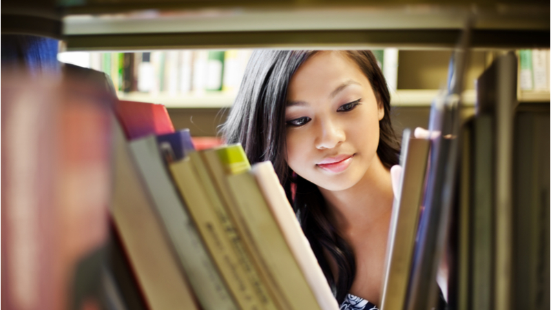 close-up of young woman searching for a book in a library