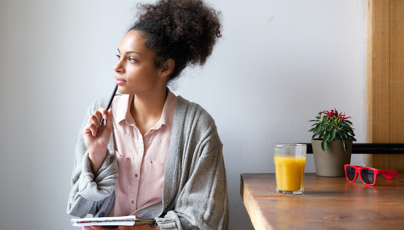 Portrait of a young woman sitting at home with pen and paper