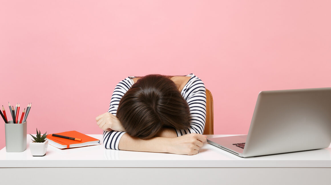 woman with head down on desk, thinking "my dissertation is killing me"