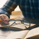 man in flannel shirt holding a pencil and reading books