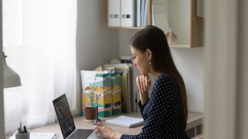 woman with eyeglasses working on her dissertation from her home office