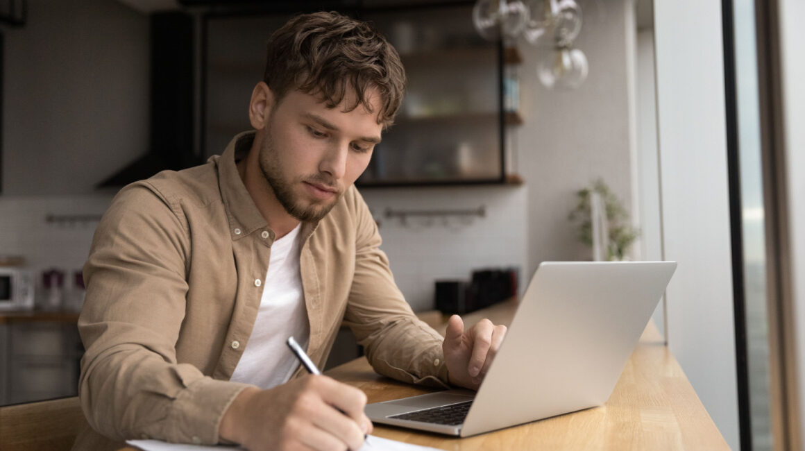 grad student preparing research on laptop in modern home kitchen