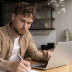 grad student preparing research on laptop in modern home kitchen