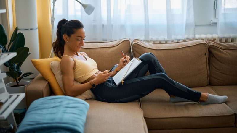 graduate student in sportswear studying at home on her couch